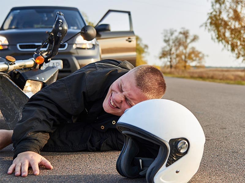 man laying on ground after motorcycle accident