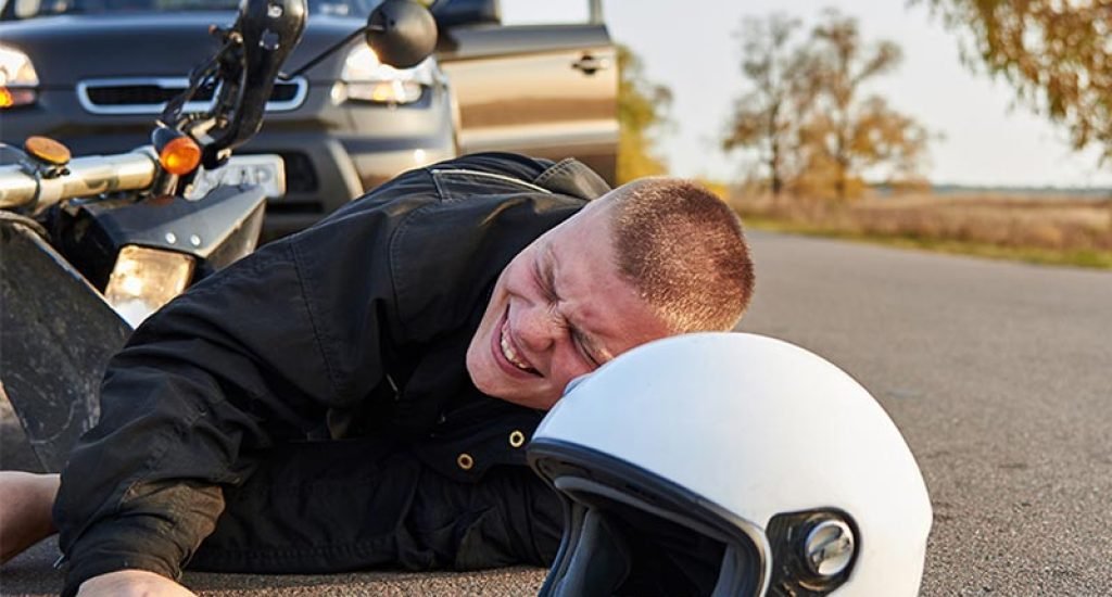 man laying on ground after motorcycle accident